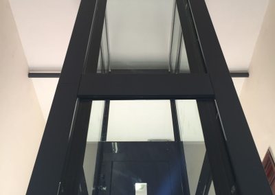 Vista da esterno retro di ascensore con struttura in lamiera di acciaio autoportante tamponata con vetro trasparente